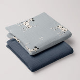 Dalmatian swaddle and navy muslin blanket folded in a stack